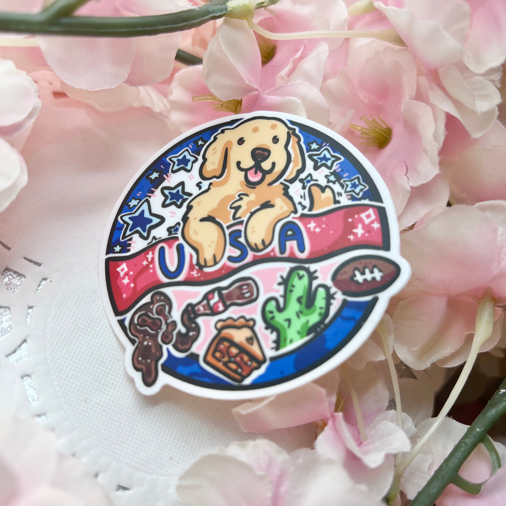 A sticker of a stamp esque circle design that says "USA" with a golden retriever inside, along with symbols like football, cactus, etc.