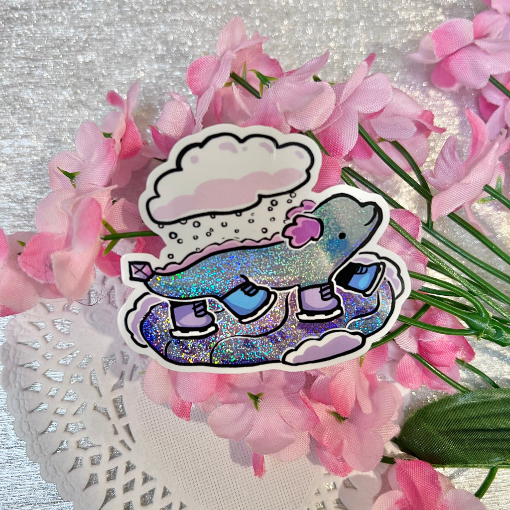 A sticker of a blue wingless dragon with ice skates skating on ice, a cloud of snow above them