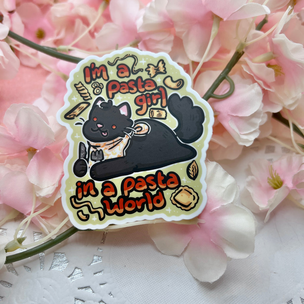 a sticker of a chonky black cat laying with a bib and utensils in hand, various pasta shapes floating around, with text that says "im a pasta girl, in a pasta world"