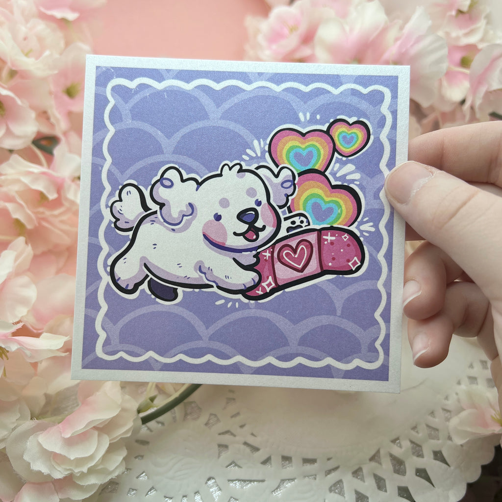 A print of a white puppy happily holding a pink bandage with rainbow hearts popping up