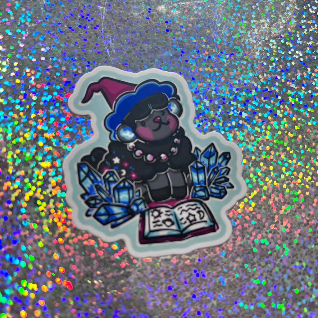 Sticker of a sheep in a witch outfit with crystals and a book on a glittery background