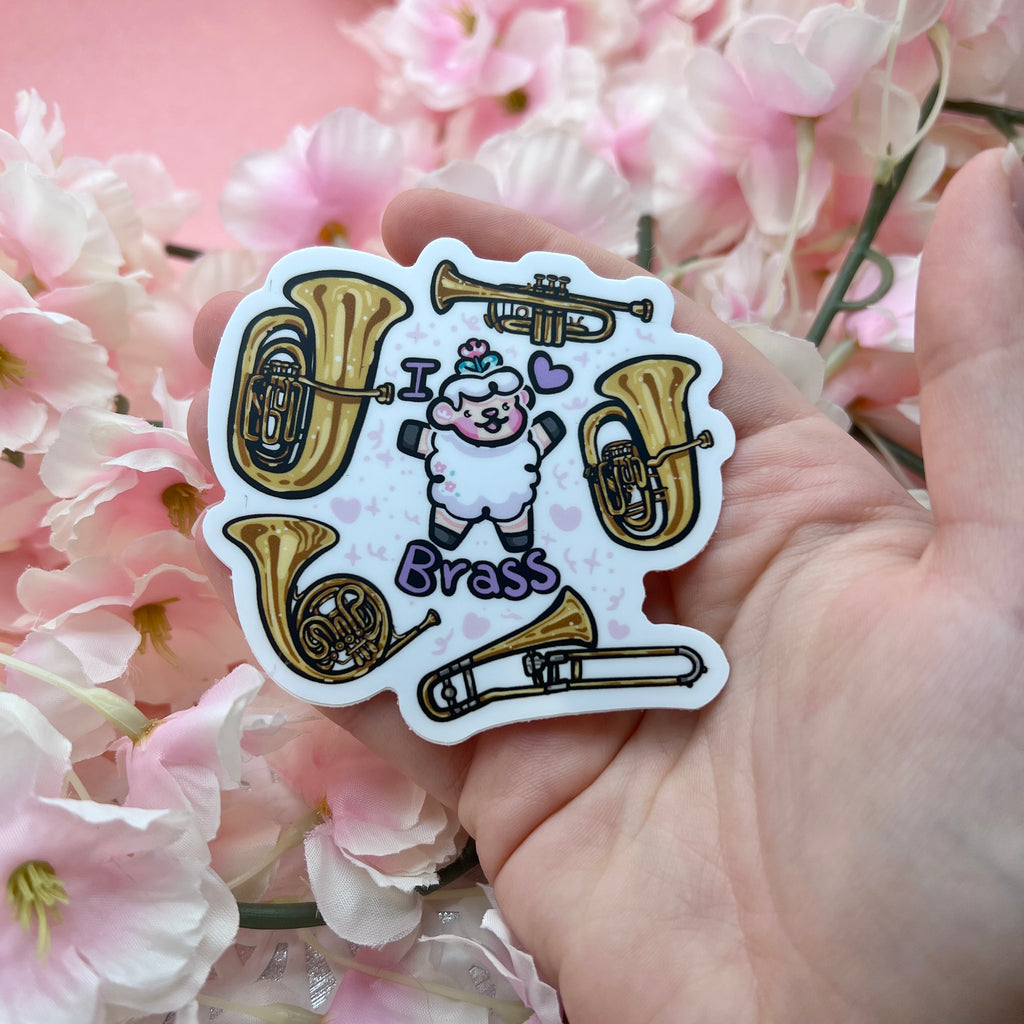 a sticker of a sheep with the text "I heart brass" and five instruments floating around them (tuba, trumpet, euphonium, trombone, and french horn)