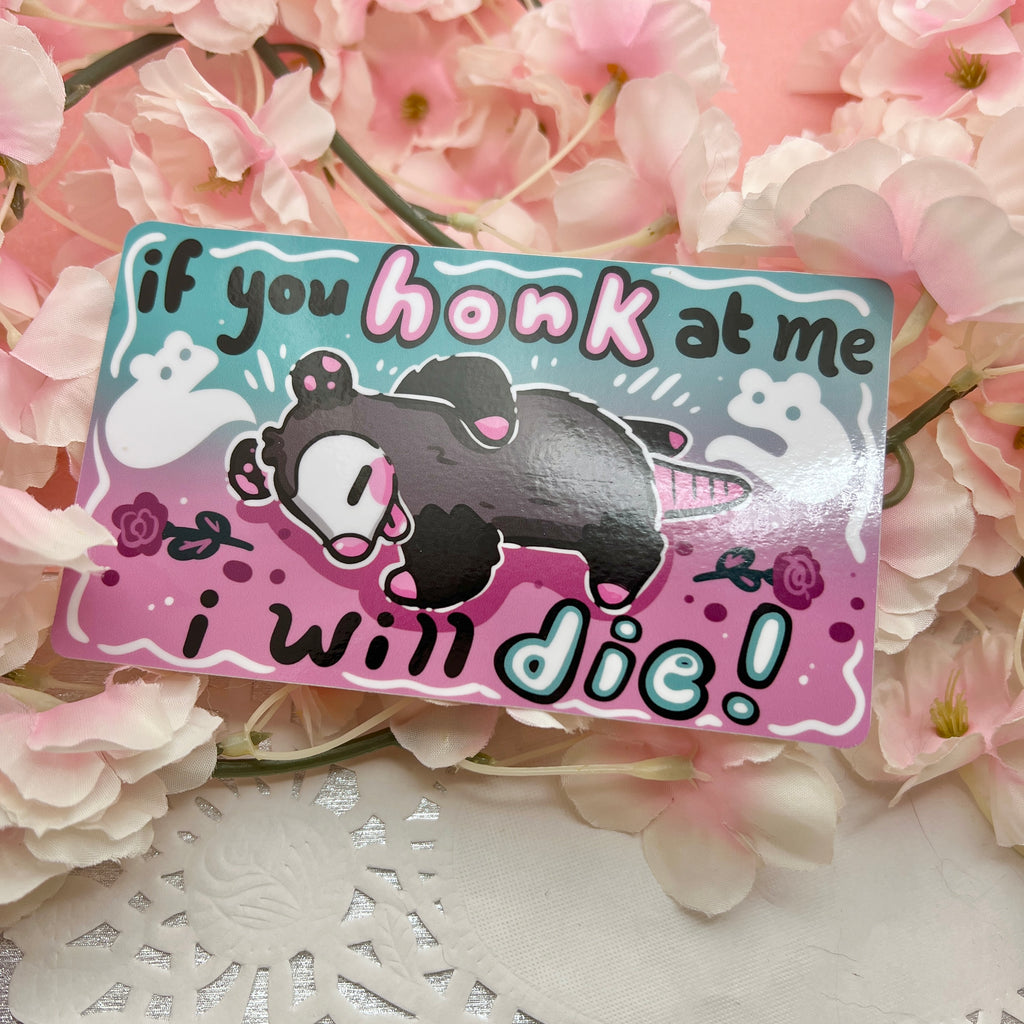 a bumper sticker of a opossum who looks dead, ghosts and flowers around it, with text that says "if you honk at me i will die"