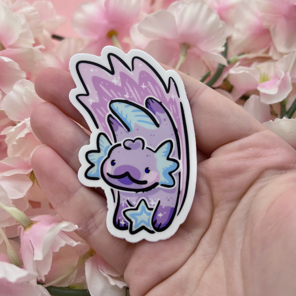 a sticker of an axolotl holding a blue shooting star- the axolotl is pastel purple and blue