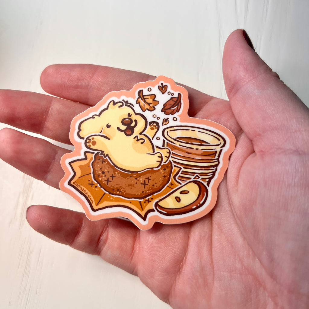 Sticker of a golden retriever on an apple doughnut held by hand