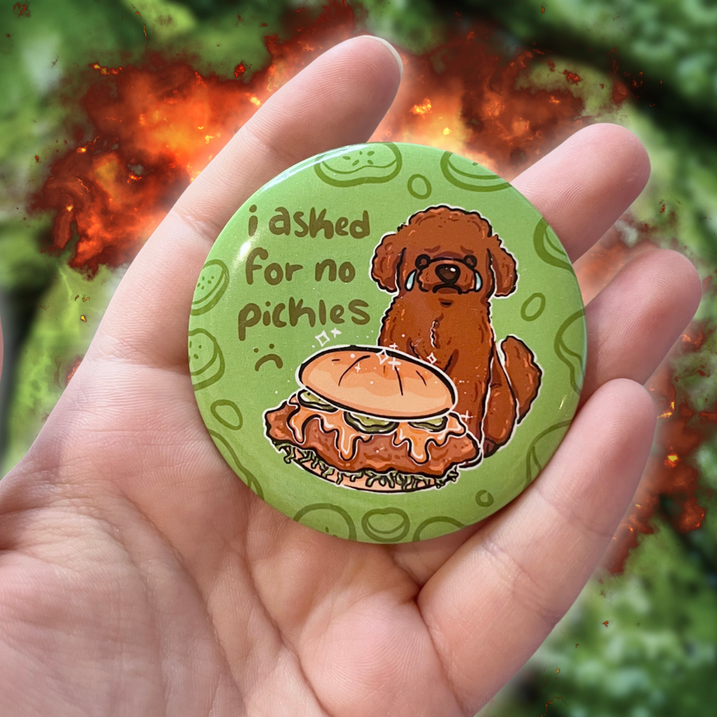 A button of a brown poodle dog sad and crying in front of a chicken sandwich that has pickles. Text says "i asked for no pickles :(" against a green background with pickle outlines