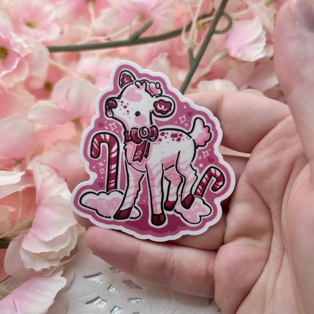 A sticker of a white deer that has pink and red accents and is peppermint themed