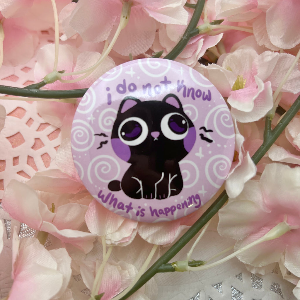 A button of a black cat looking blankly confused against a pale pink/purple background that has white swirls. Text around them says "i do not know what is happening"