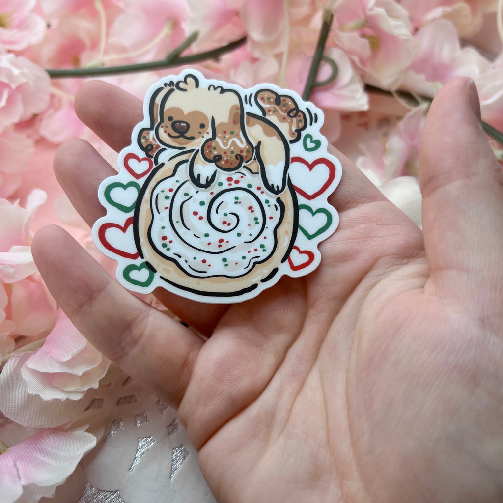 A sticker of a puppy on top of a sugar cookie with white, green, and red accents