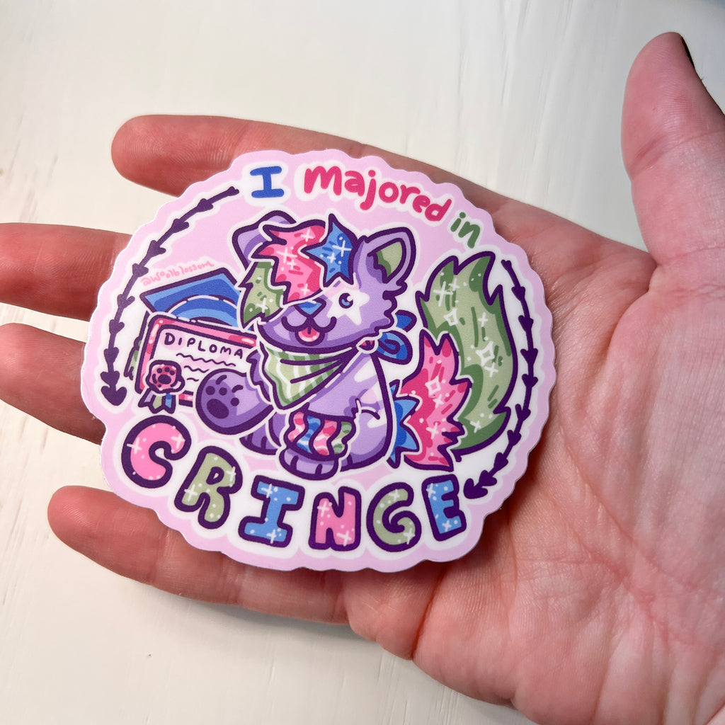 Colorful sticker with a cartoon sparkle dog and text that says "i majored in cringe" held in a hand against a white background