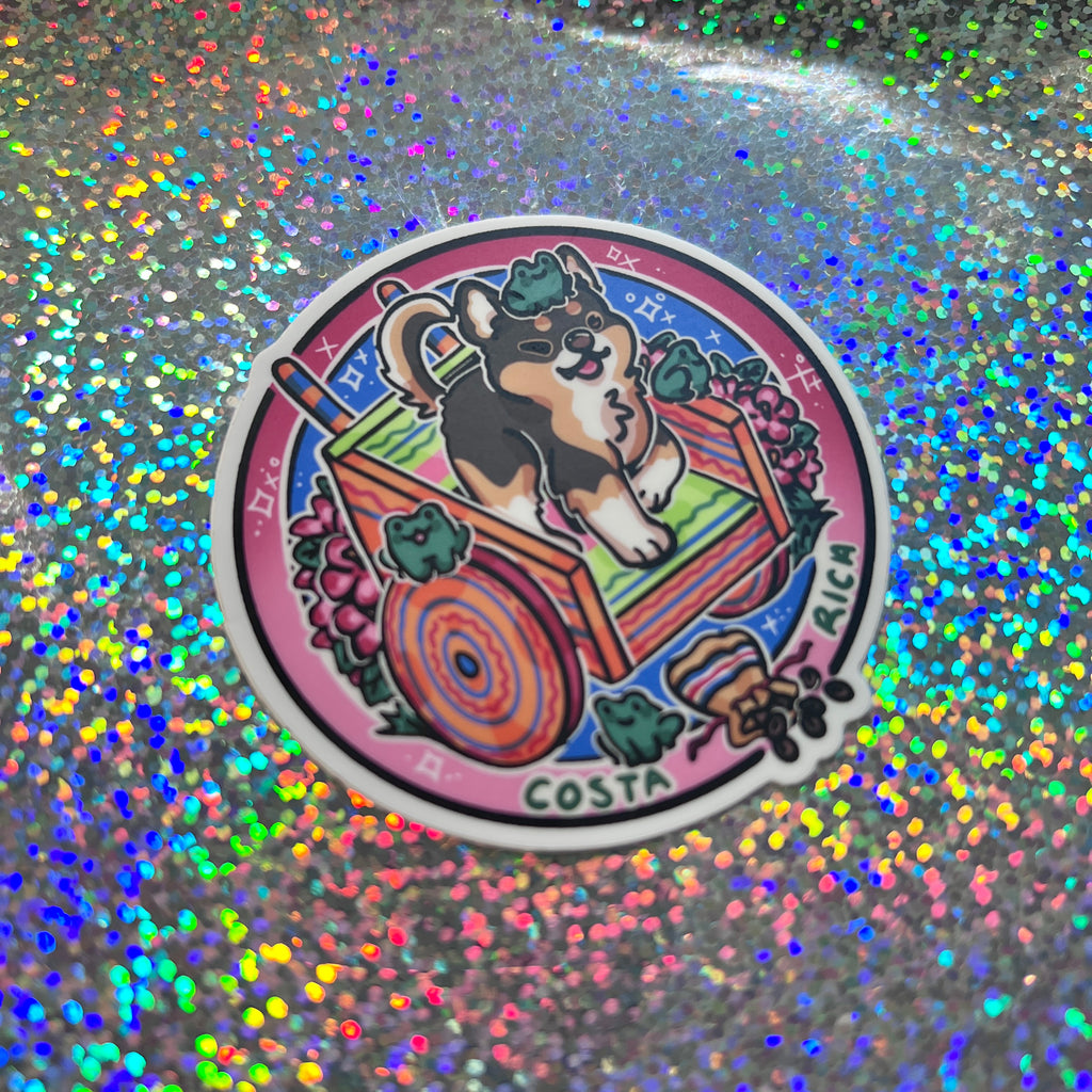 a sticker of a chihuahua on a decorative cart, surrounded by flowers, frogs, and chocolate on a glittery background