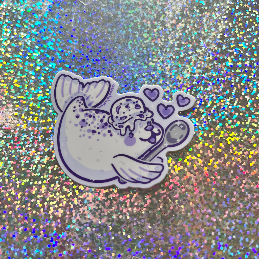 a sticker of a cookies and cream seal against a glittery background