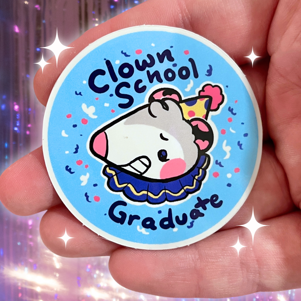 Circular sticker with cartoon character opossum and text 'Clown School Graduate' held in a hand against a glittery background.