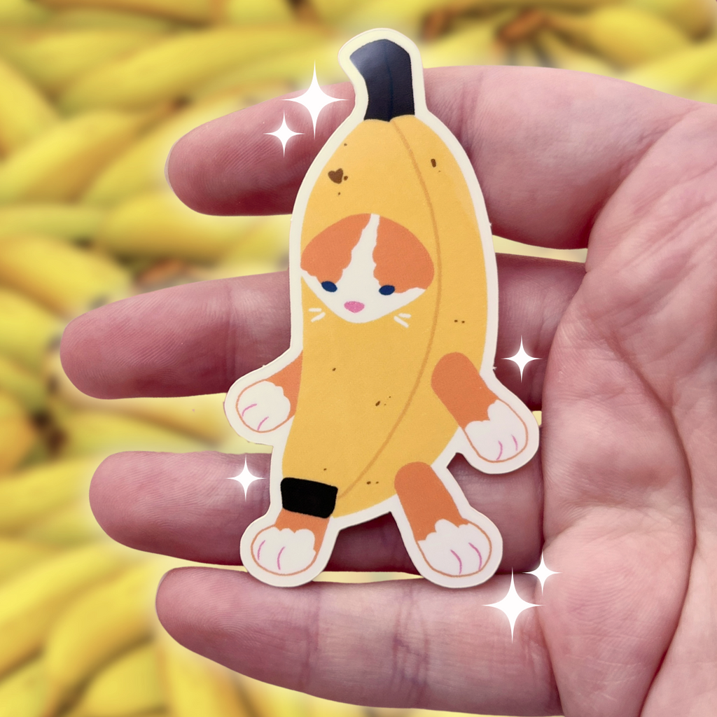 Cartoon character cat in a banana costume sticker held in a hand with a blurred banana background