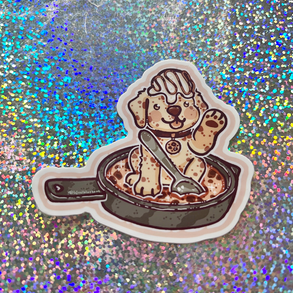 Sticker of a cookie dog on a cookie skillet on a glittery background