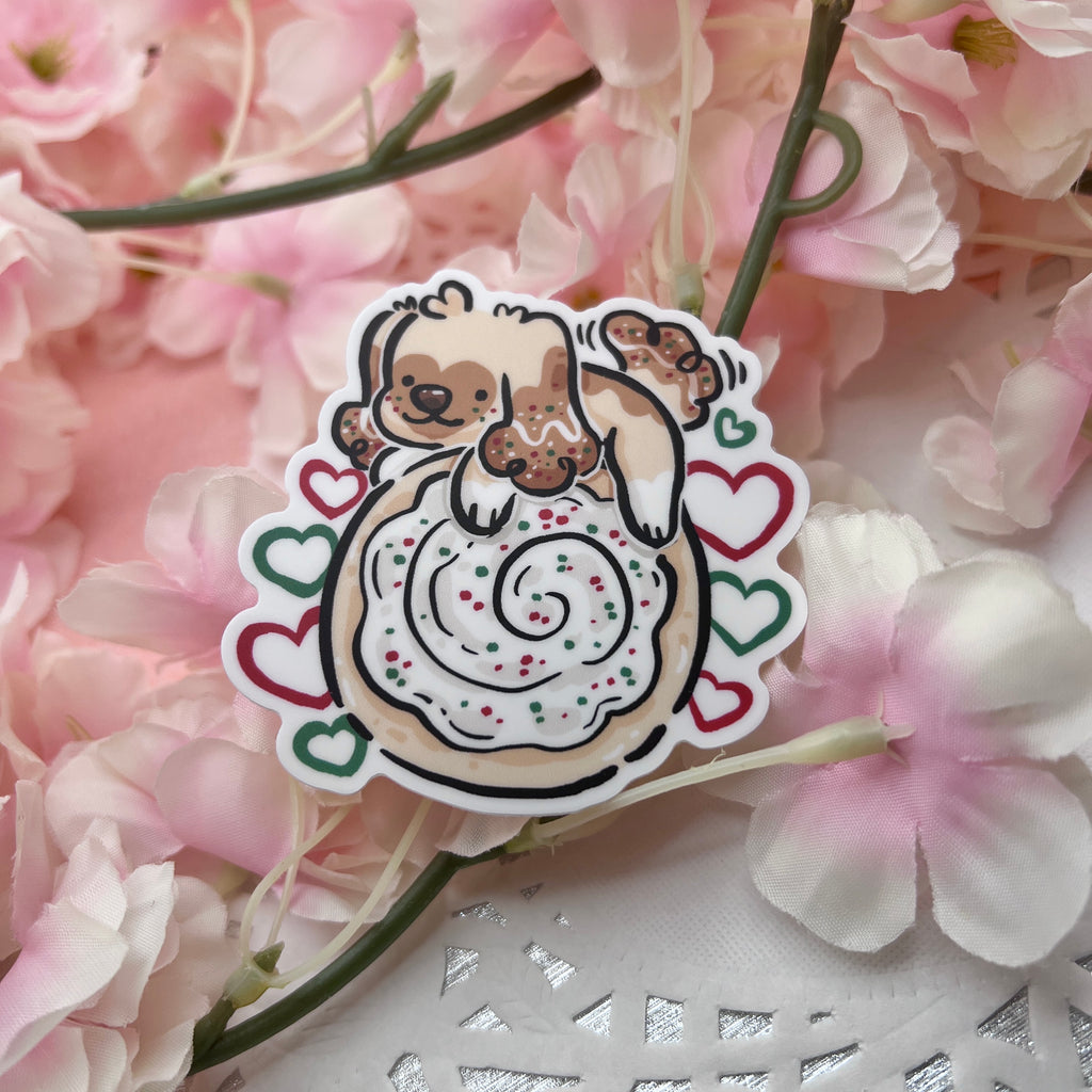 A sticker of a puppy on top of a sugar cookie with white, green, and red accents