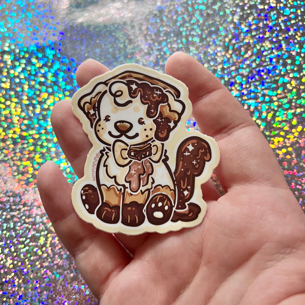 Hand holding a cartoon dog sticker with a glittery background