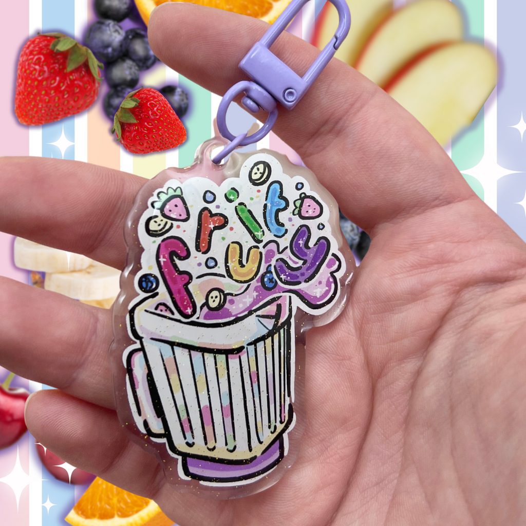 A acrylic keychain charm of a blender with fruit floating out and bubble rainbow text that says "fruity"