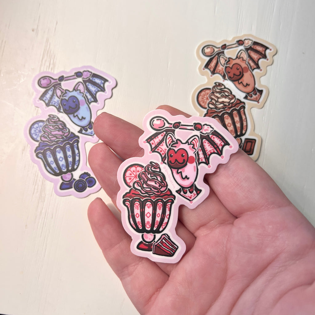 colorful bat-themed stickers that are stain glass and ice cream themed held by hand