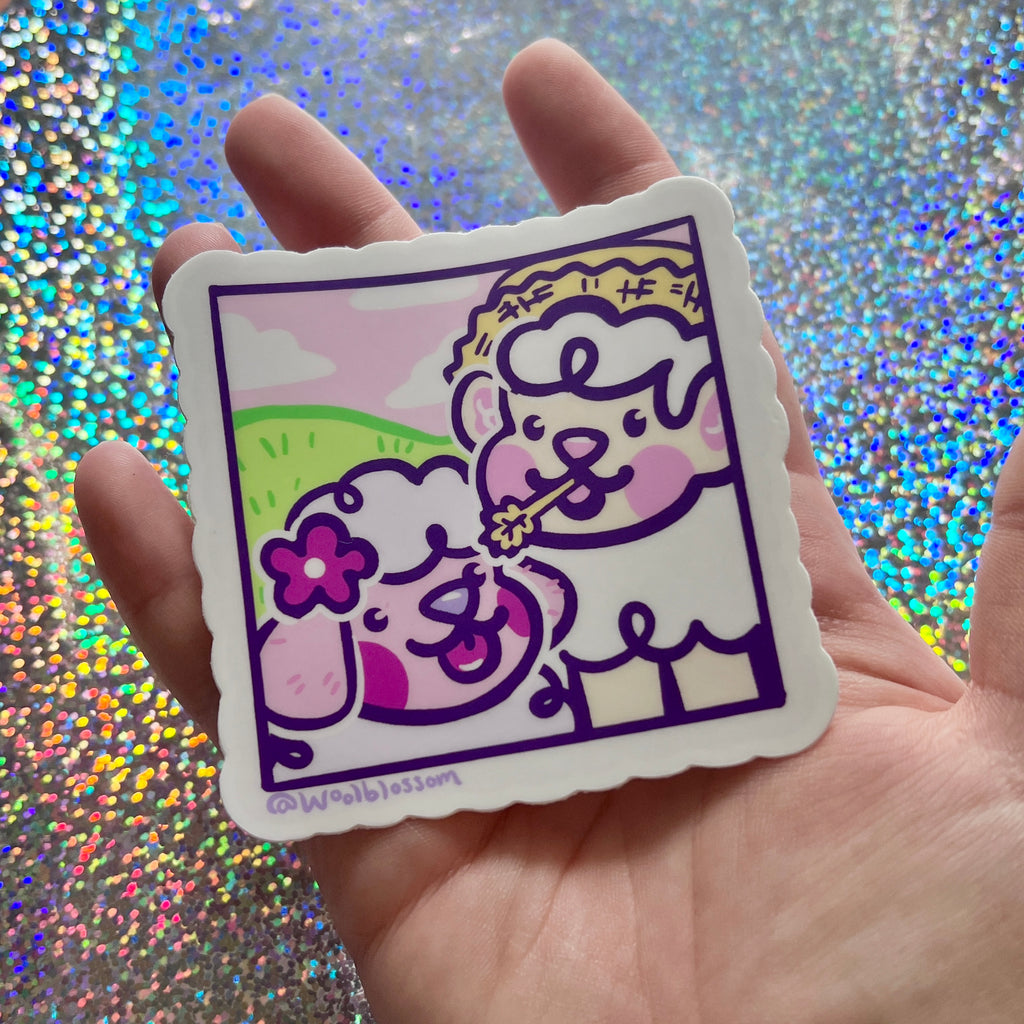 Hand holding a Cartoon sticker of a sheep and dog together on a farm against a glittery background