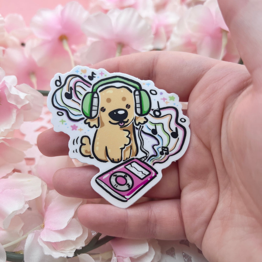 A sticker of a golden retriever with headphones on listening to a retro music player with rainbow music staff and notes