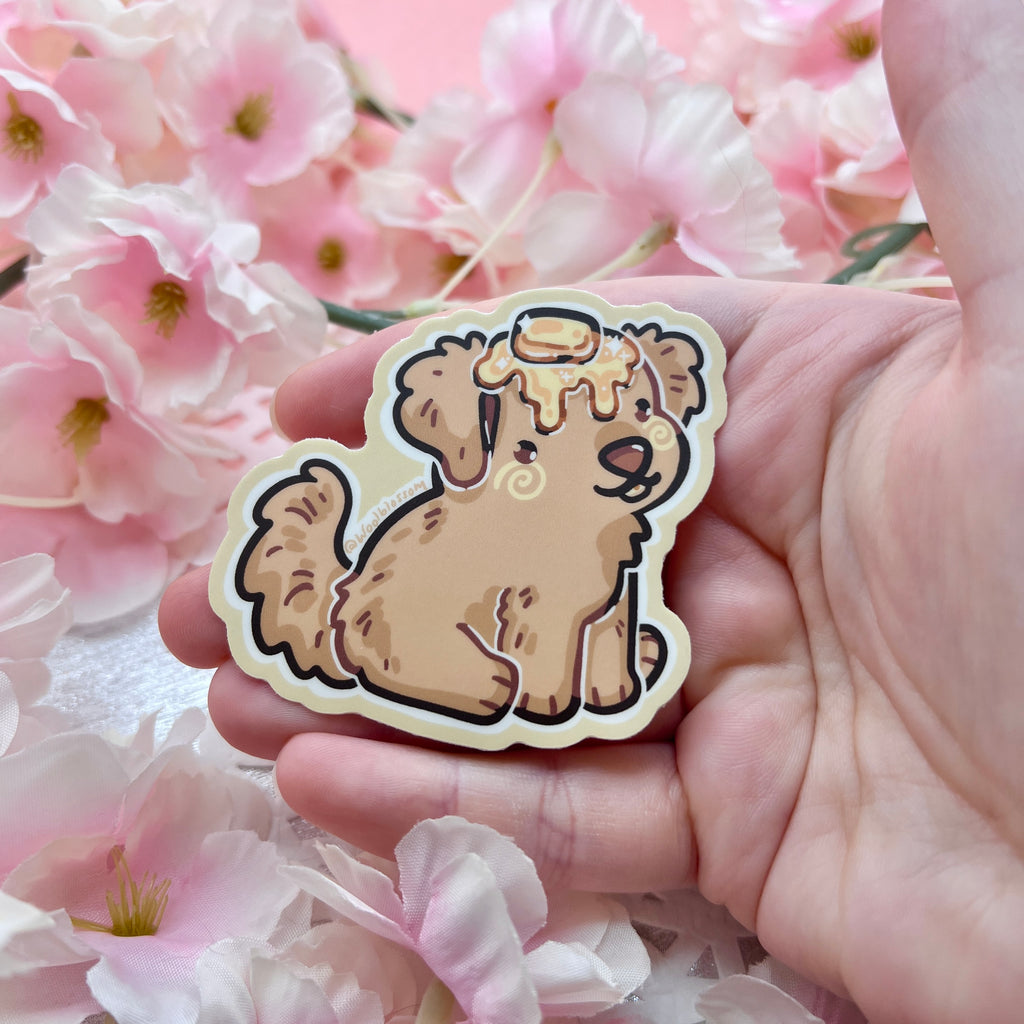 A sticker of a golden retriever puppy with butter on its head