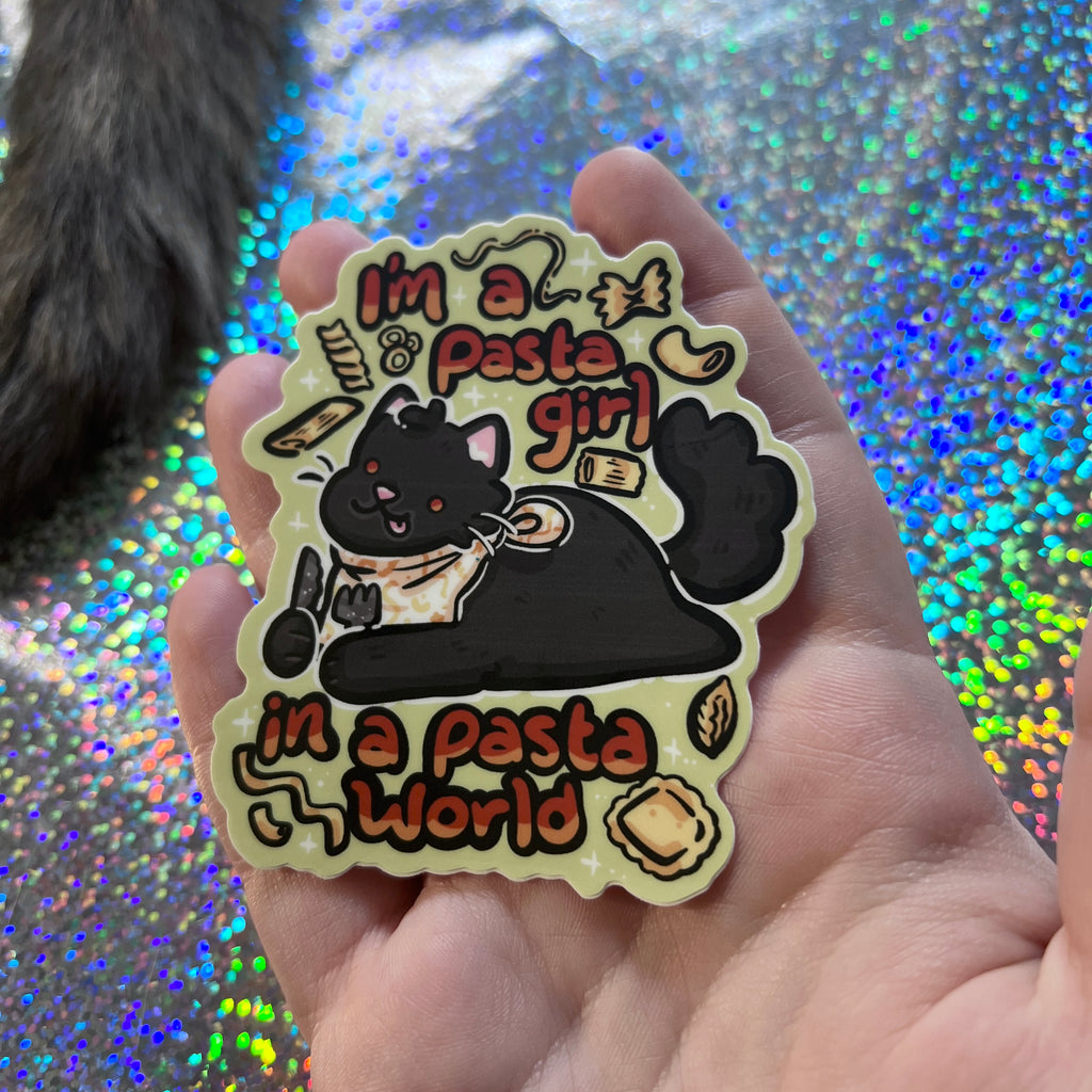 Hand holding a sticker with a cat holding a knife and fork with pasta floating around, text 'I'm a pasta girl in a pasta world against a glittery background.