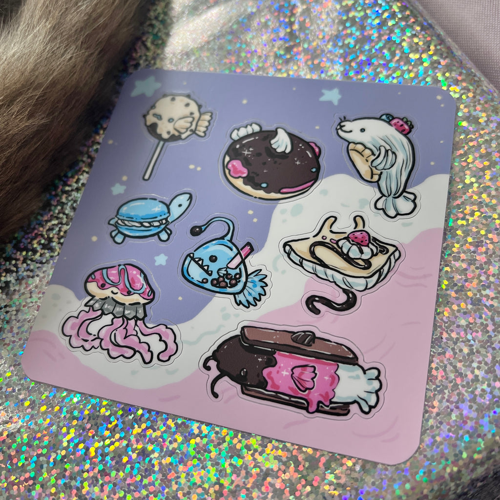 Cartoon stickers of food item sea creatures on a colorful sticker sheet on a glittery background
