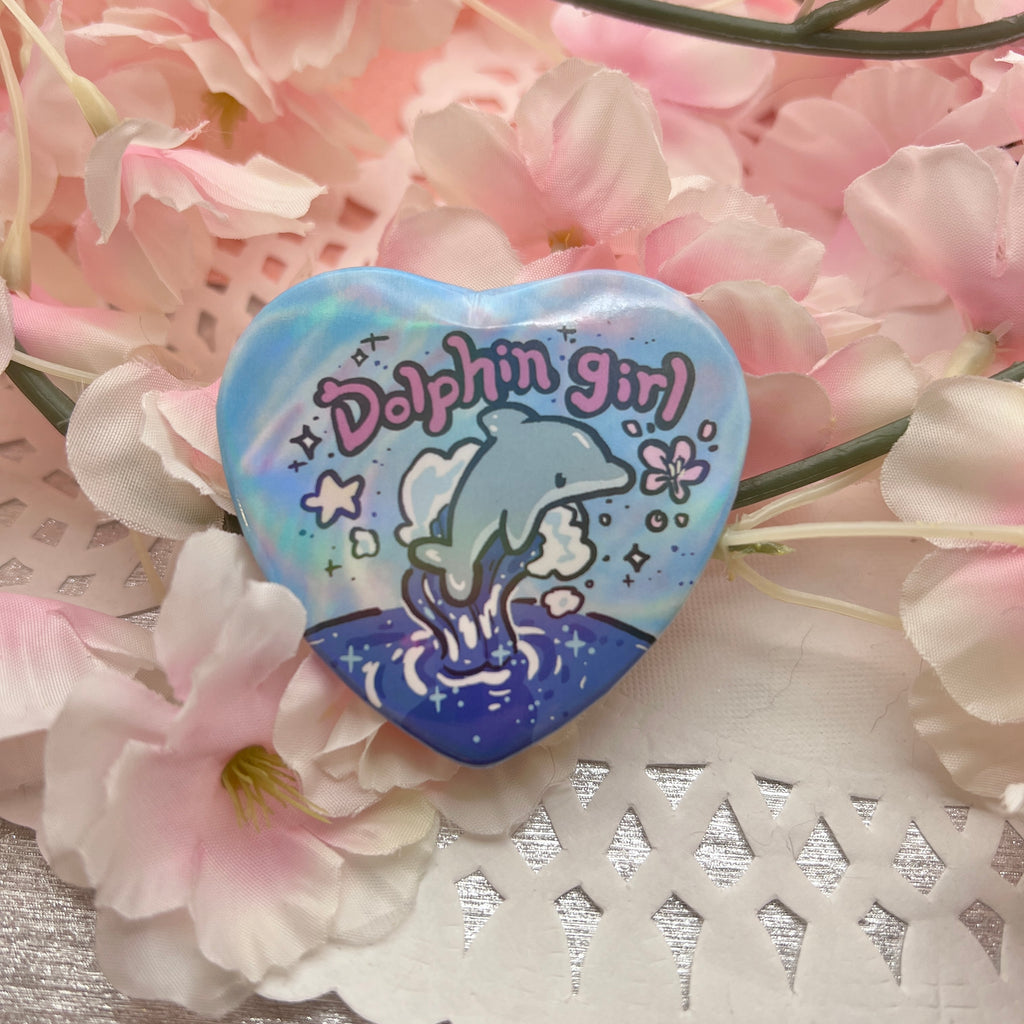 a heart button that says dolphin girl with a dolphin jumping out of the ocean