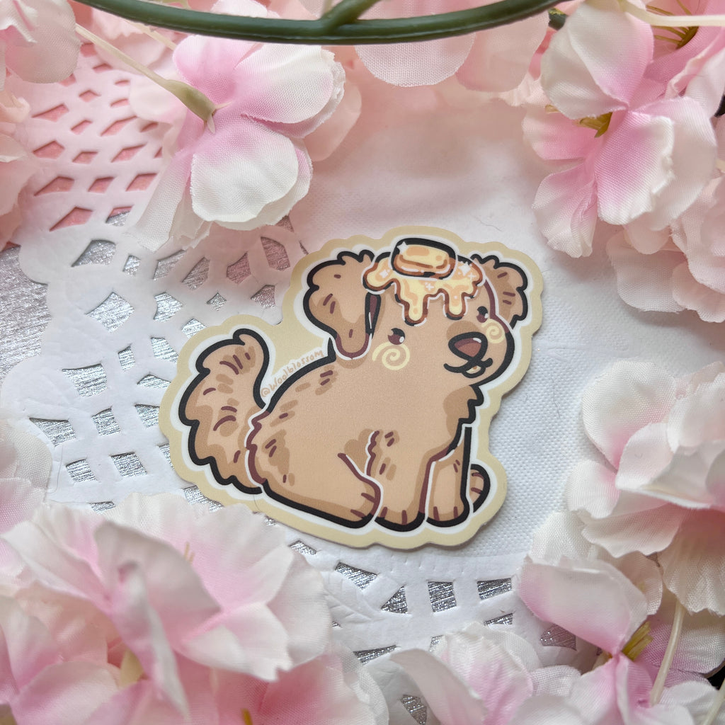 A sticker of a golden retriever puppy with butter on its head