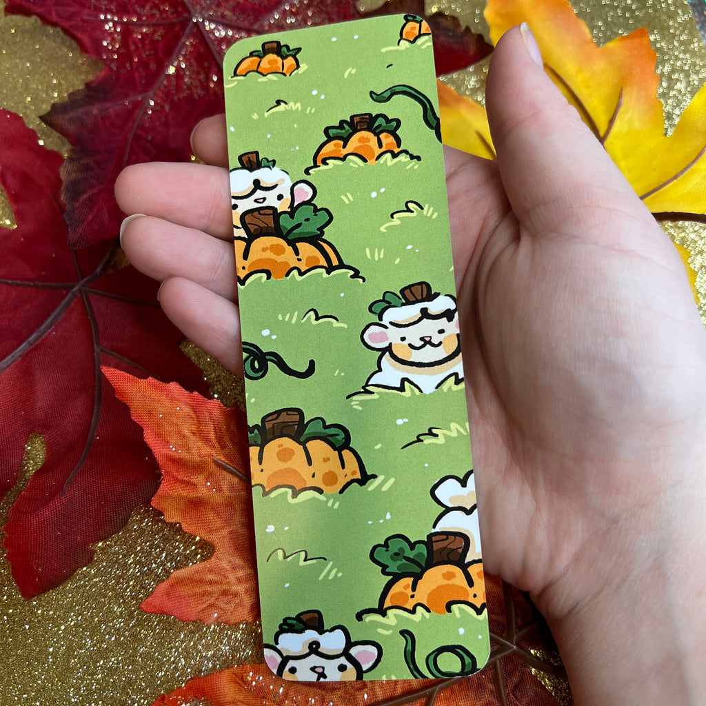 A bookmark of a pumpkin patch with a white sheep sticking their head up across the design