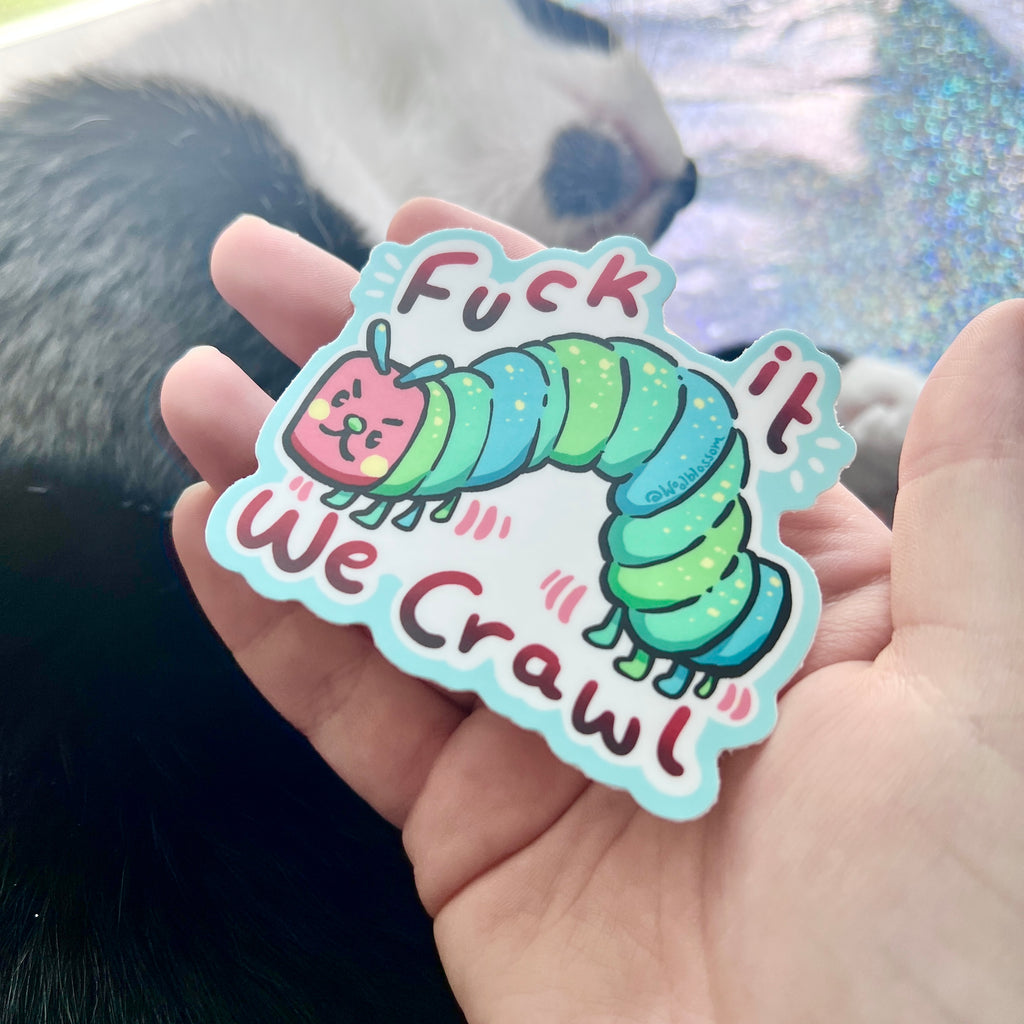 Sticker with a colorful caterpillar design and text held in a hand.