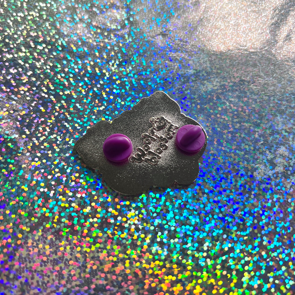 An enamel pin of two otters floating together holding heart shaped seashells