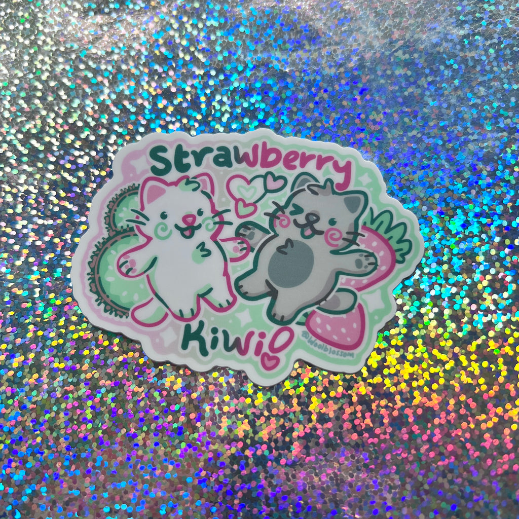 Two cats next to each other with strawberries and kiwis and text that says "strawberry kiwi!"