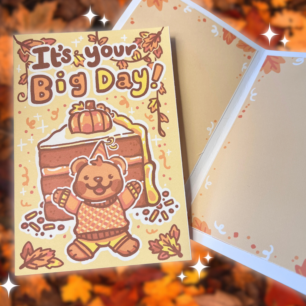 Greeting card with a bear holding a cake and 'It's your Big Day!' text, surrounded by autumn leaves.