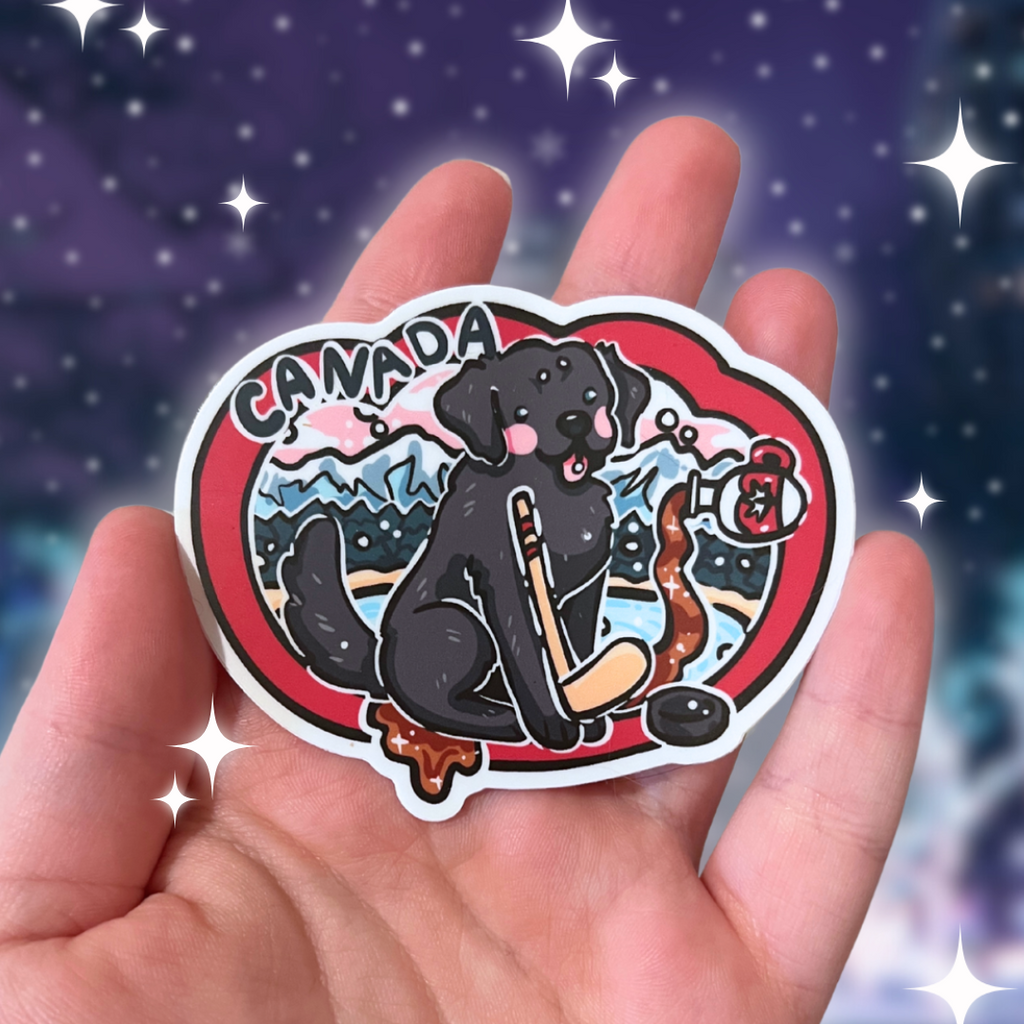 Hand holding a sticker with a black dog, hockey stick, and 'Canada' text against a starry night sky.