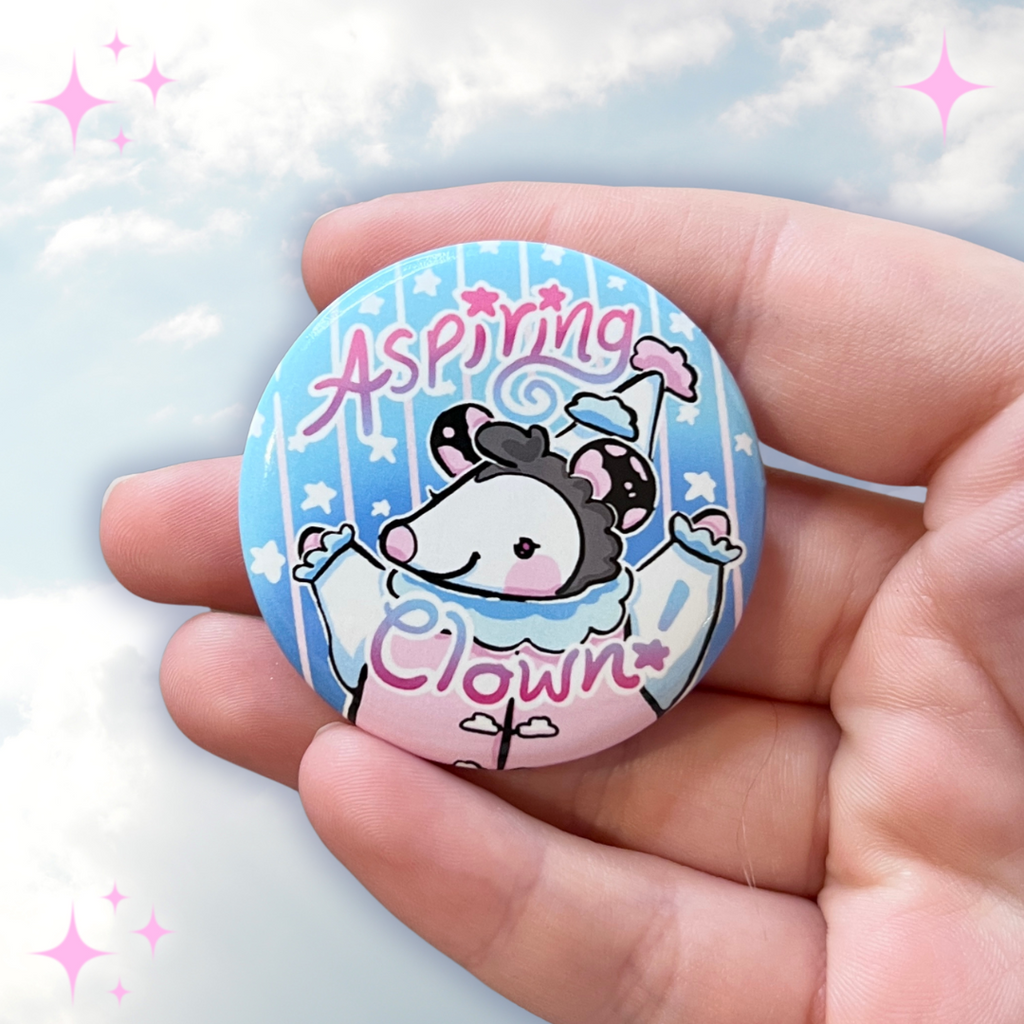 A button of a cloud themed opossum that looks happy with the text "aspiring clown"