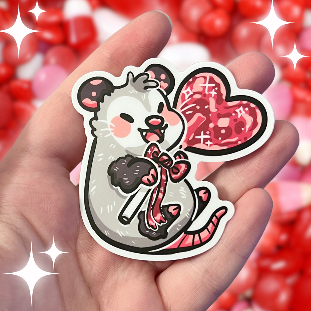 A sticker of an opossum happily holding a red heart lollipop