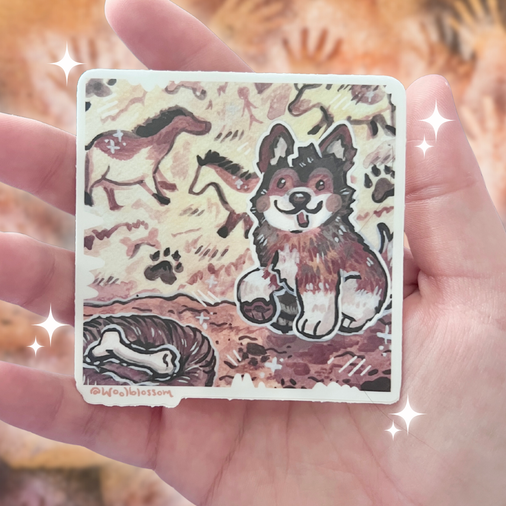 Card with a dog illustration of a cave art painter puppy held in a hand against a blurred background