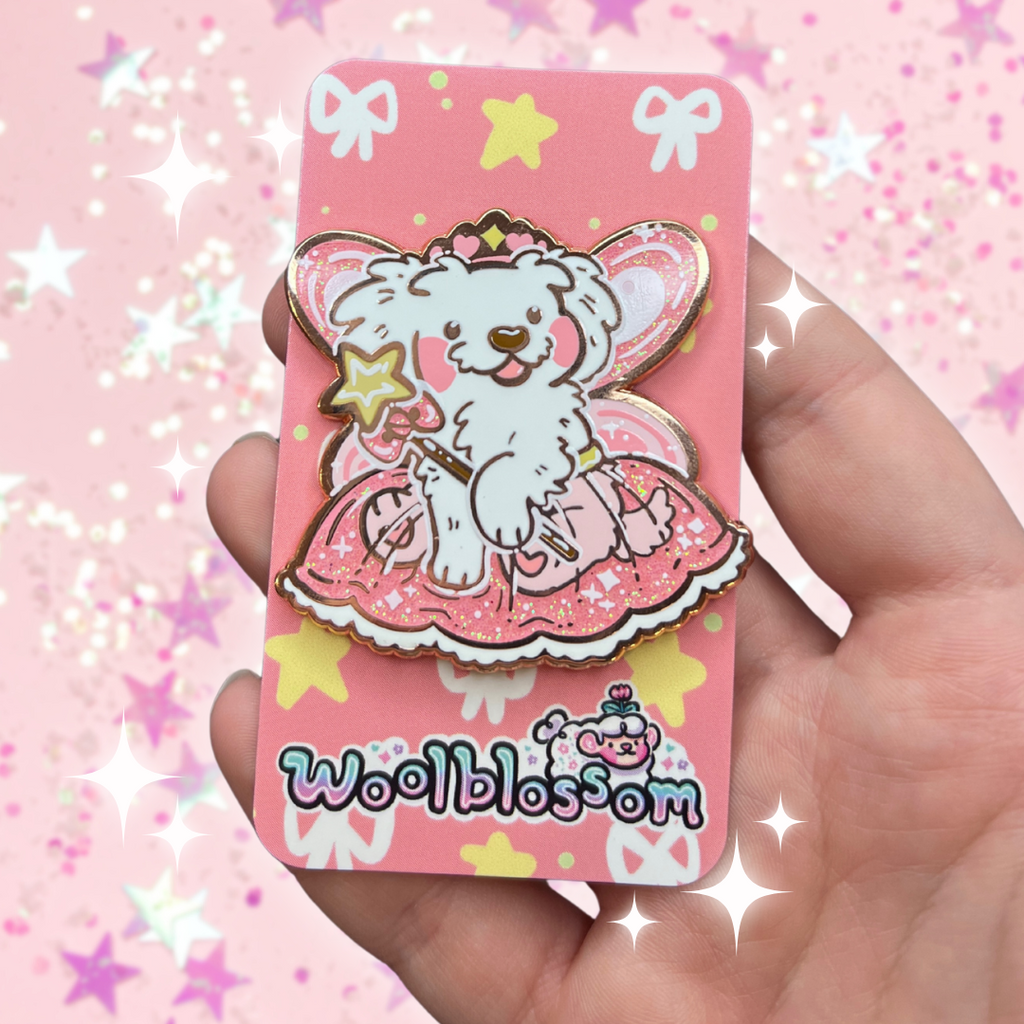 An enamel pin of a white puppy with fairy wings, star wand, tutu, and princess crown