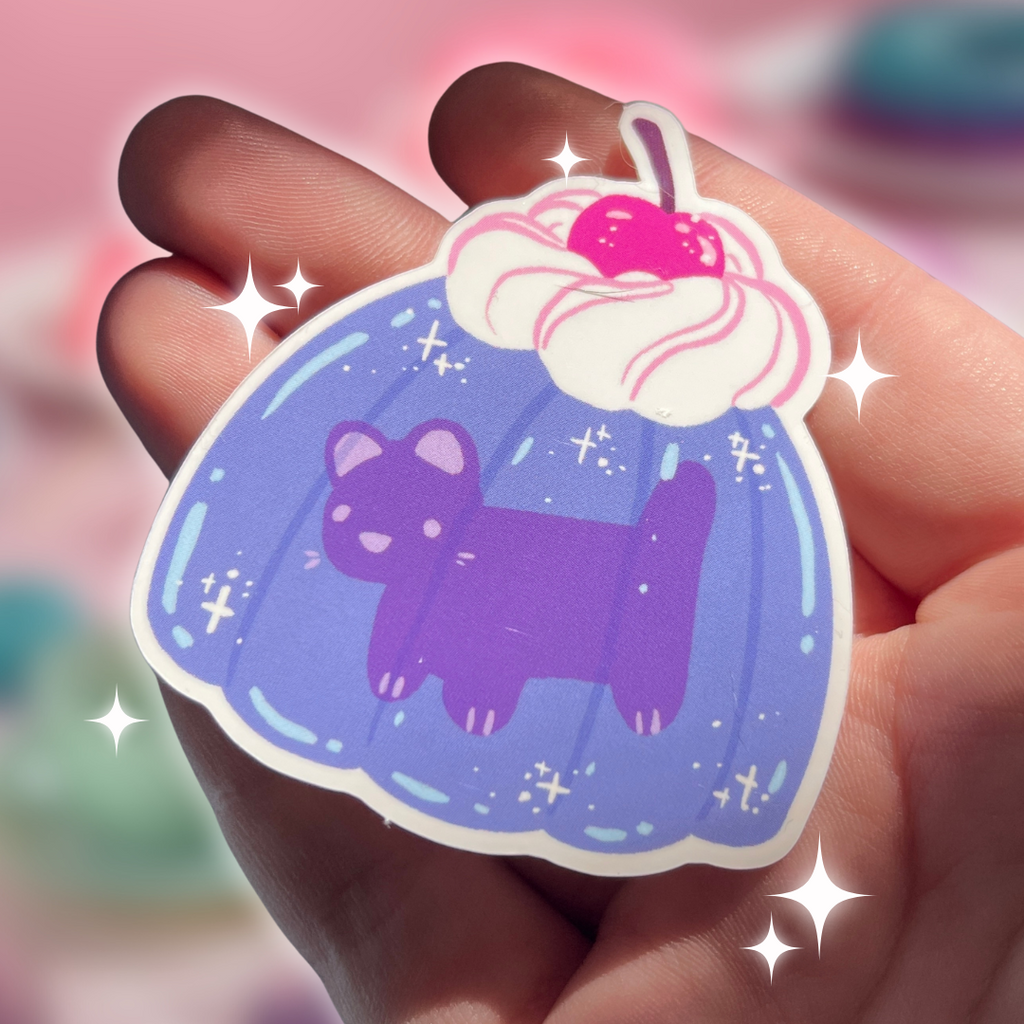 Sticker of a purple cat in a purple gelatin held in a hand with a colorful background