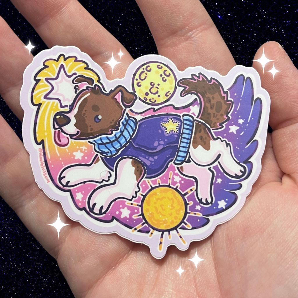 Sticker of a dog in a space suit in space held in a hand against a dark background