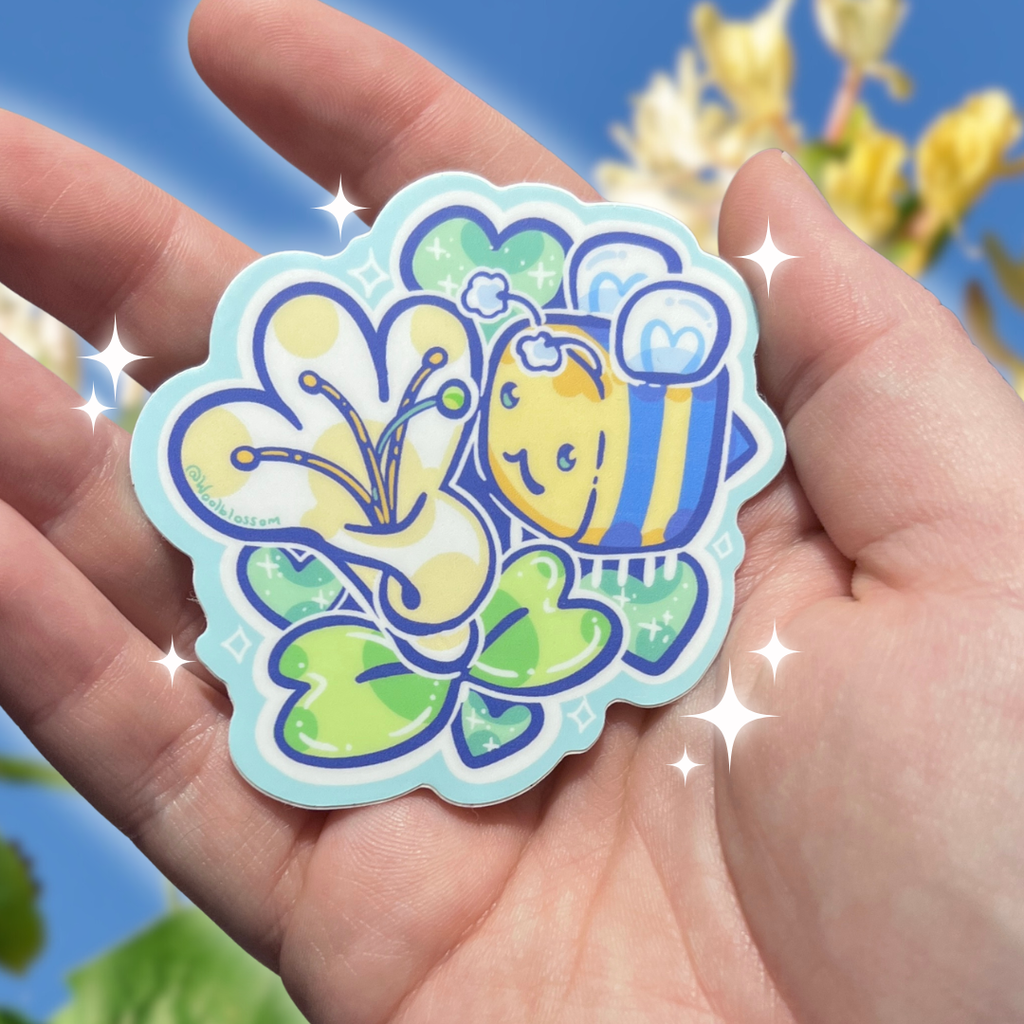 Colorful sticker of a bee and flower held in a hand with a blurred floral background