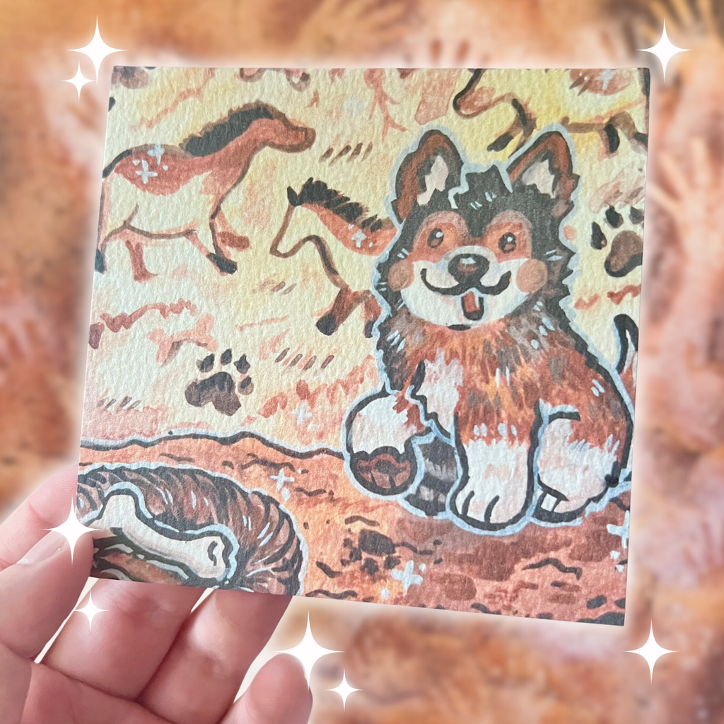 Card with a dog illustration of a cave art painter puppy held in a hand against a blurred background