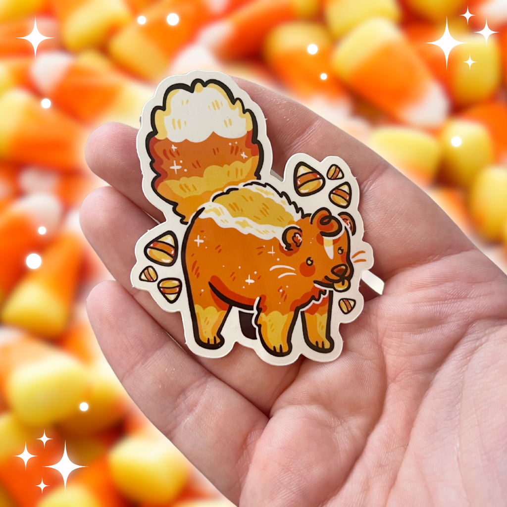 A sticker of a candy corn colored skunk