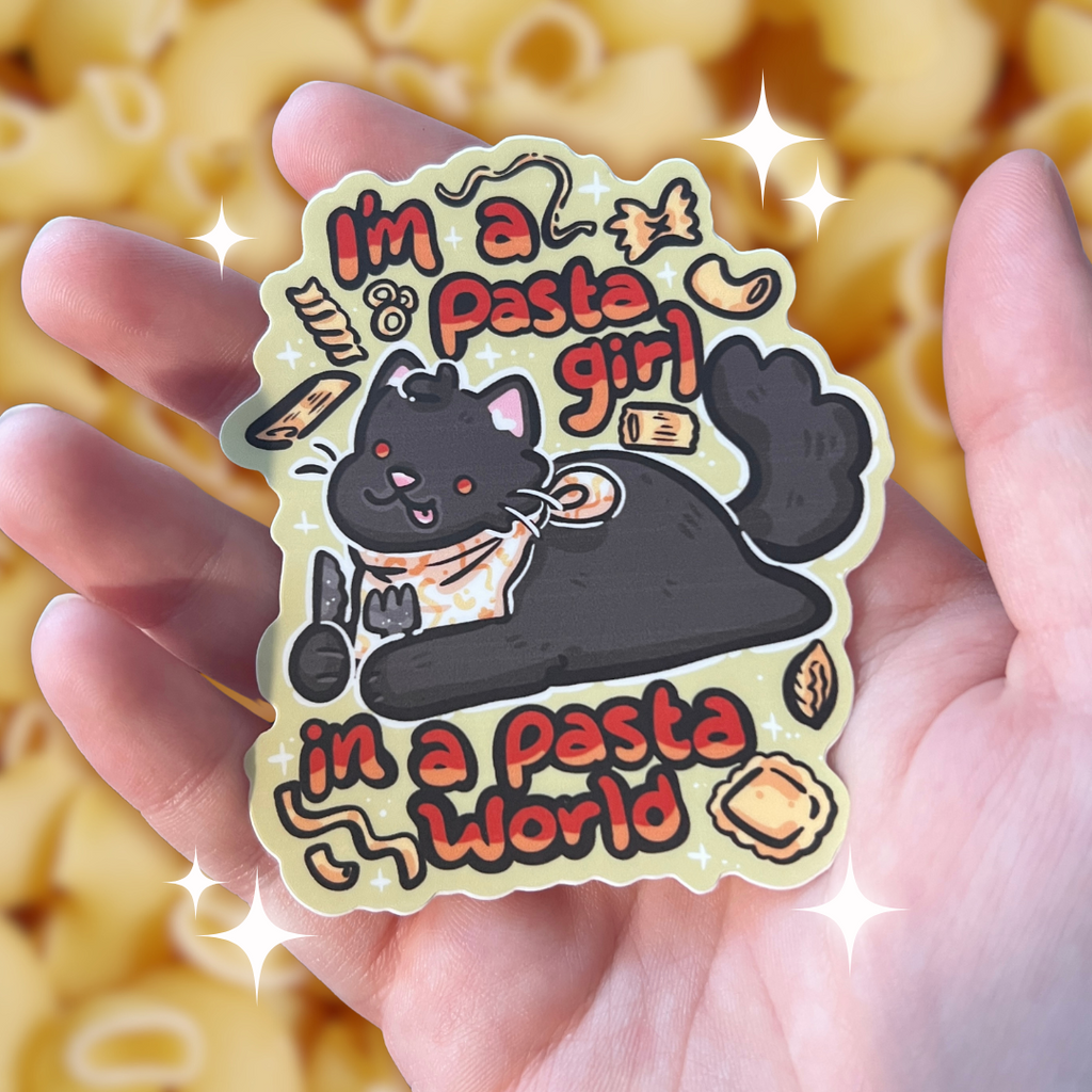 Sticker with a cat holding a knife and fork with pasta floating around, text 'I'm a pasta girl in a pasta world', held in a hand with pasta in the background.