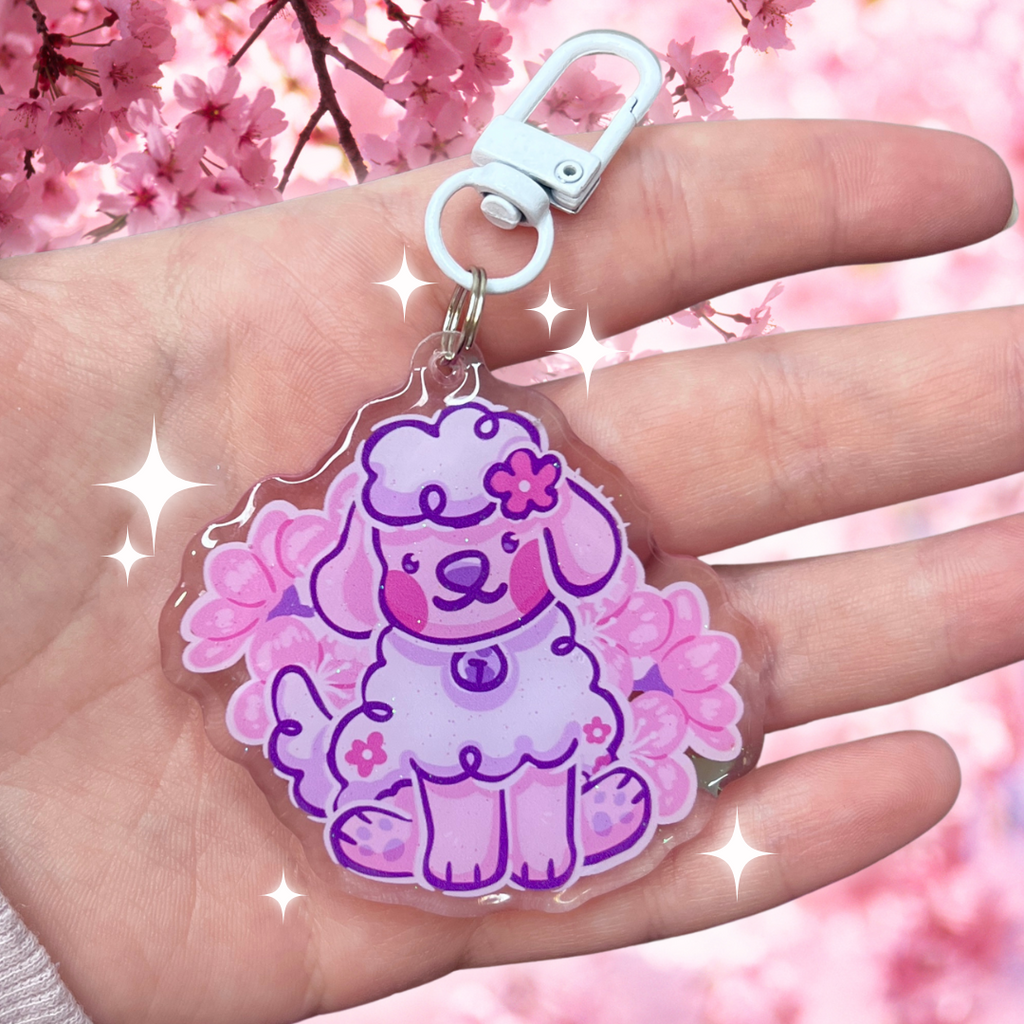 Keychain of cherry blossom the dog sitting with cherry blossoms behind her